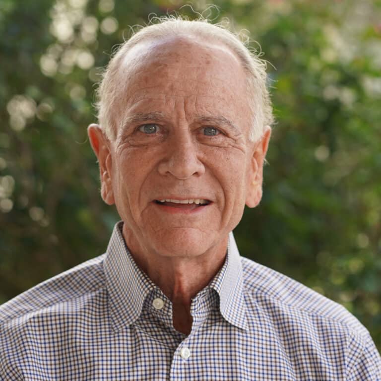 Smiling elderly man outdoors with greenery background