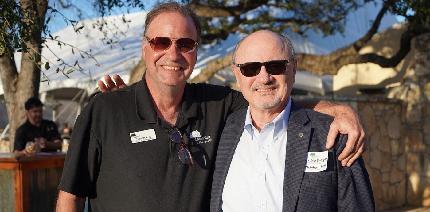 Two men wearing sunglasses posing outdoors together