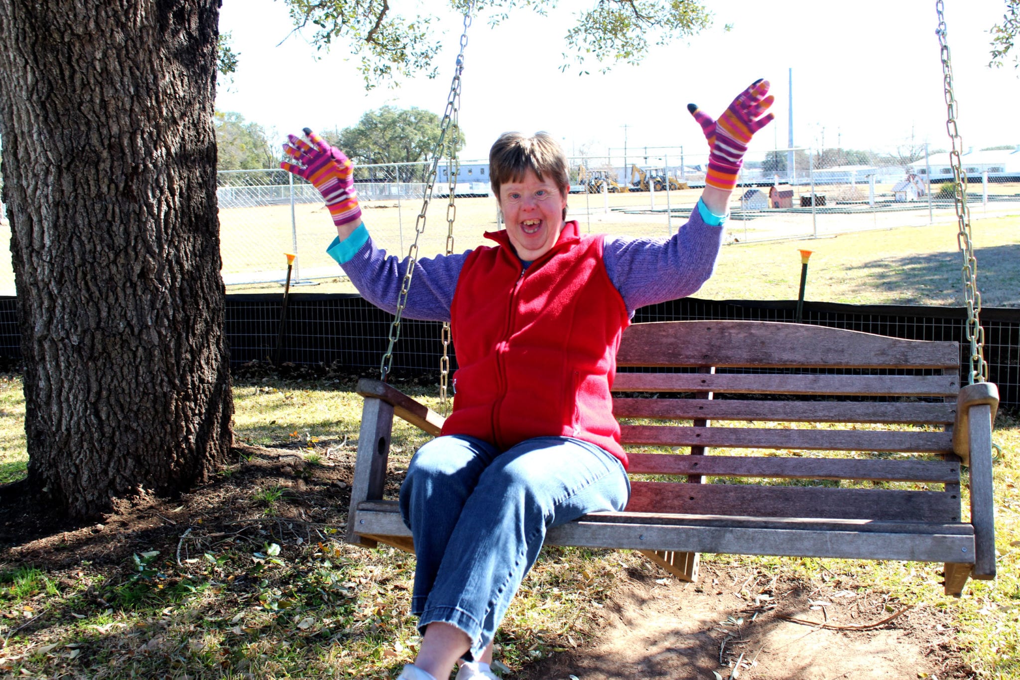 A smiling woman sitting on a swing.