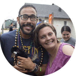 A man wearing Mardi Gras beads and holding a bunny posing for a picture with a woman.