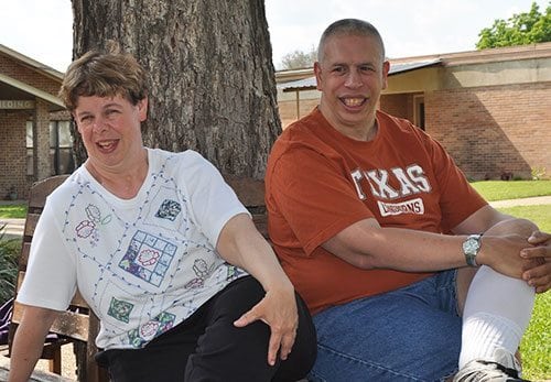 A man and a woman sitting on a bench and smiling.