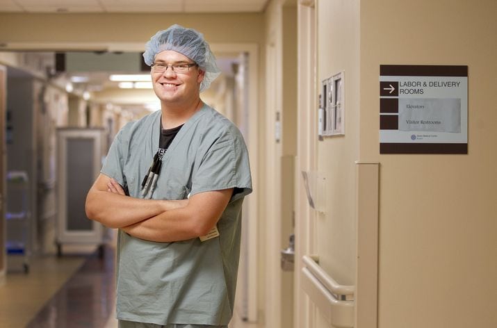 A man in scrubs standing in a hospital hallway.