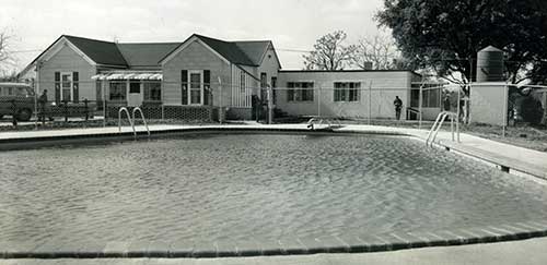 An old photo of a swimming pool outside of the original Ranch House.